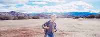 a young man standing in the middle of a desert