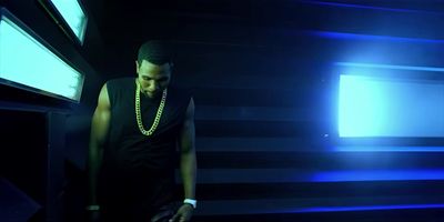 a man standing in a dark room with a necklace on