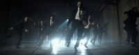 a group of men in suits and ties dancing in the dark