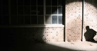 a person sitting on the ground in front of a brick building