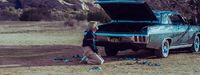 a young boy standing next to a parked car