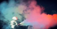 a fireman spraying colored smoke into the air