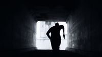 a silhouette of a person standing in a dark tunnel