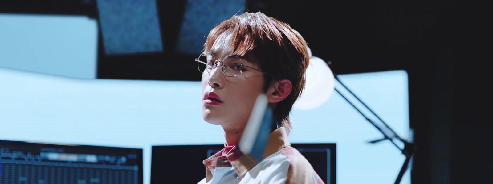 a man with glasses and a tie standing in front of a computer screen