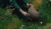 a person in a green jacket is holding a bucket