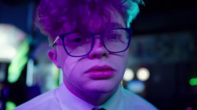 a man wearing glasses and a tie in a dark room