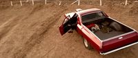 a red pick up truck parked on a dirt road