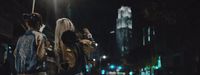 a man and a woman walking down a street at night