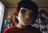 a close up of a doll wearing a red shirt