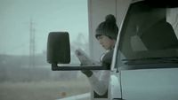 a woman reading a newspaper in front of a truck