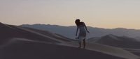 a woman standing on top of a sand dune