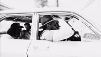 a black and white photo of a man driving a car