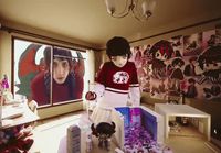 a young girl standing in front of a doll house