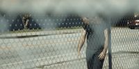 a man standing behind a chain link fence