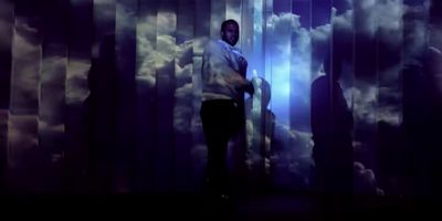 a man standing in front of a wall with clouds