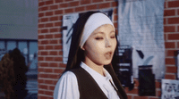 a woman in a nun costume standing in front of a brick building