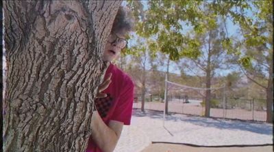 a man in a red shirt holding onto a tree