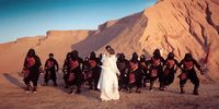 a woman in a wedding dress standing in front of a group of men