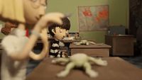 a toy figure of a boy and a frog on a desk