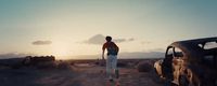 a man walking away from a car in the desert