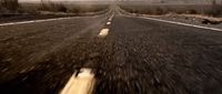 a car driving down an empty road in the middle of nowhere