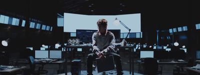 a man sitting on a chair in a room full of computer monitors