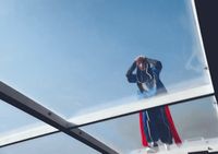 a man standing on top of a white boat under a blue sky