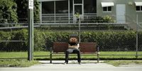 a person sitting on a bench in front of a building