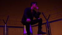 a man sitting on top of a metal fence