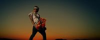 a man standing on top of a hill at sunset