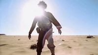 a man walking across a desert covered in sand