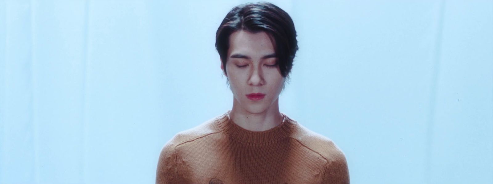 a man with his eyes closed wearing a sweater