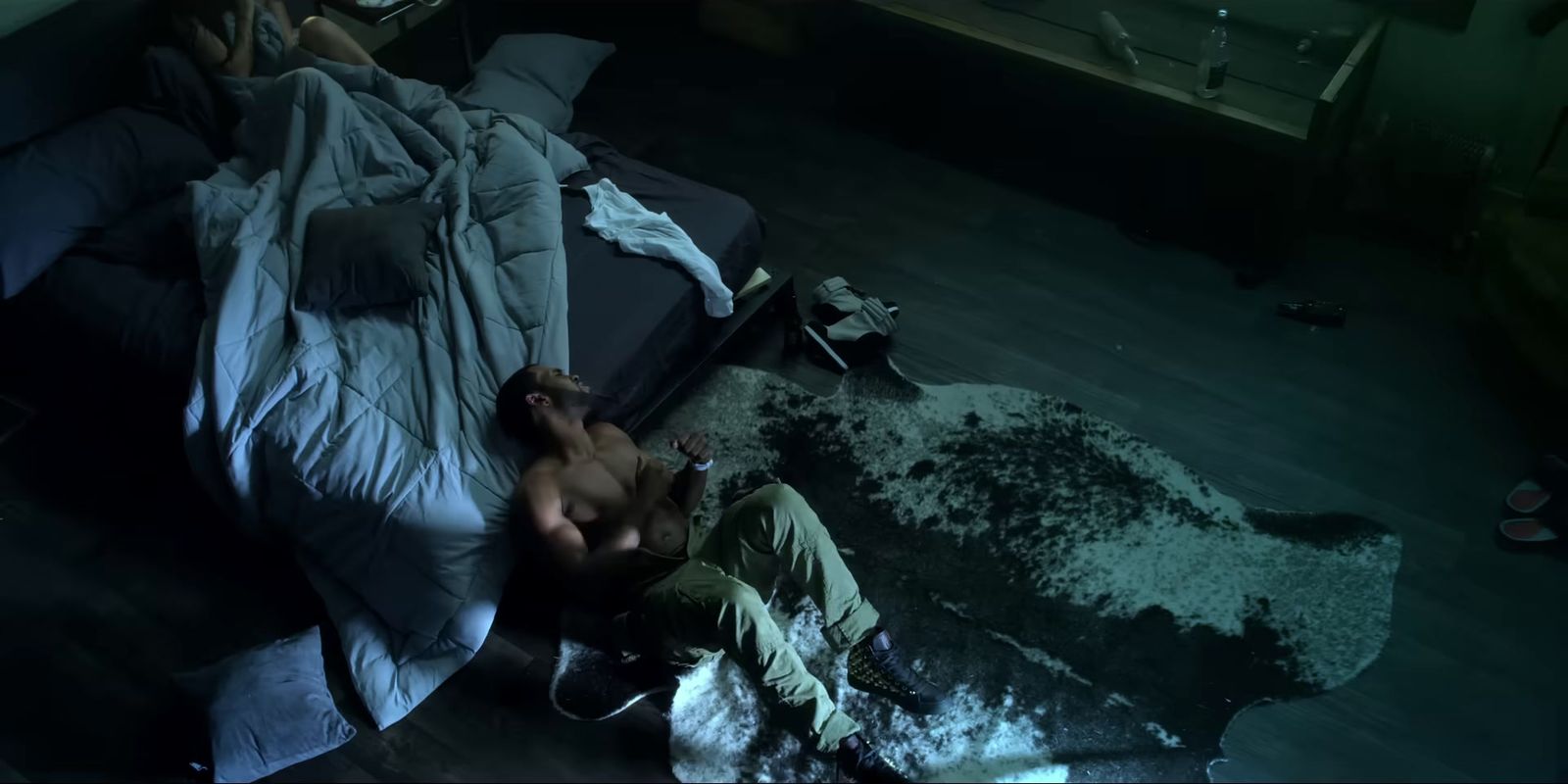 a shirtless man laying on a bed in a dark room