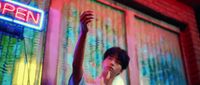 a young man standing in front of a neon sign