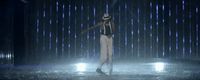 a man standing in the rain with a hat on