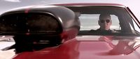 a man driving a red car on a beach