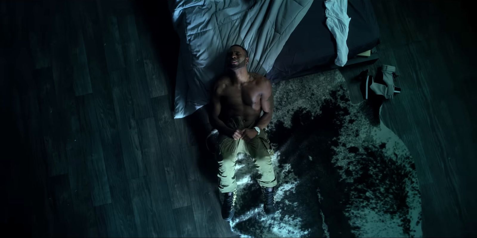 a shirtless man laying on a bed in a dark room