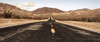 a car driving down a road with mountains in the background