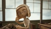 a clay model of a girl with glasses sitting at a desk