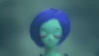 a green doll with blue hair and pink eyes