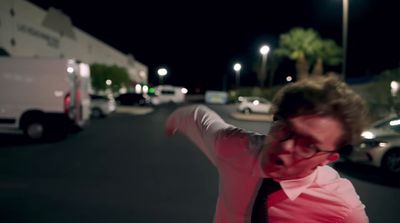 a man in a pink shirt and tie pointing at something