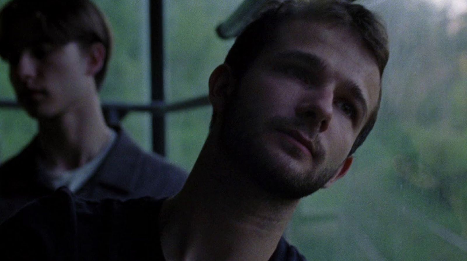 two young men looking out a window at the rain