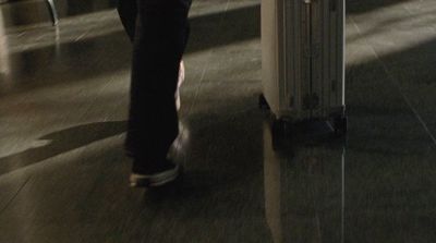 a man walking through an airport carrying a suitcase