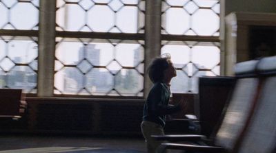 a little boy standing in front of a window