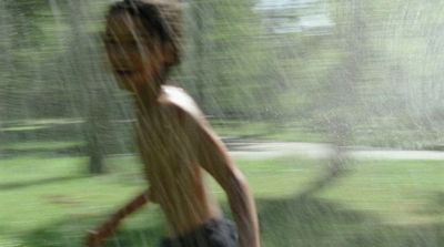 a boy running in the rain with a frisbee