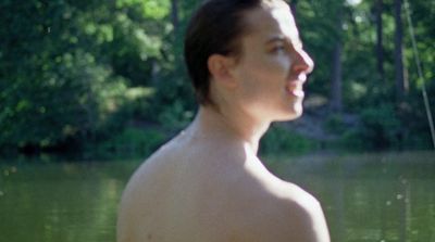 a man standing in a body of water next to a forest