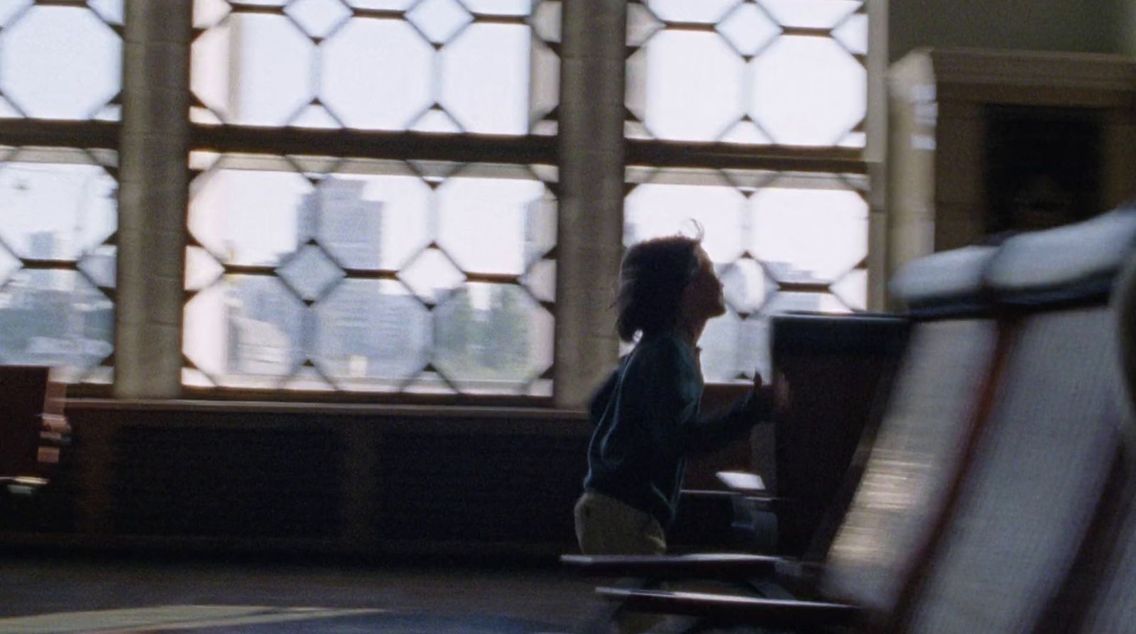 a little boy sitting on a bench in front of a window