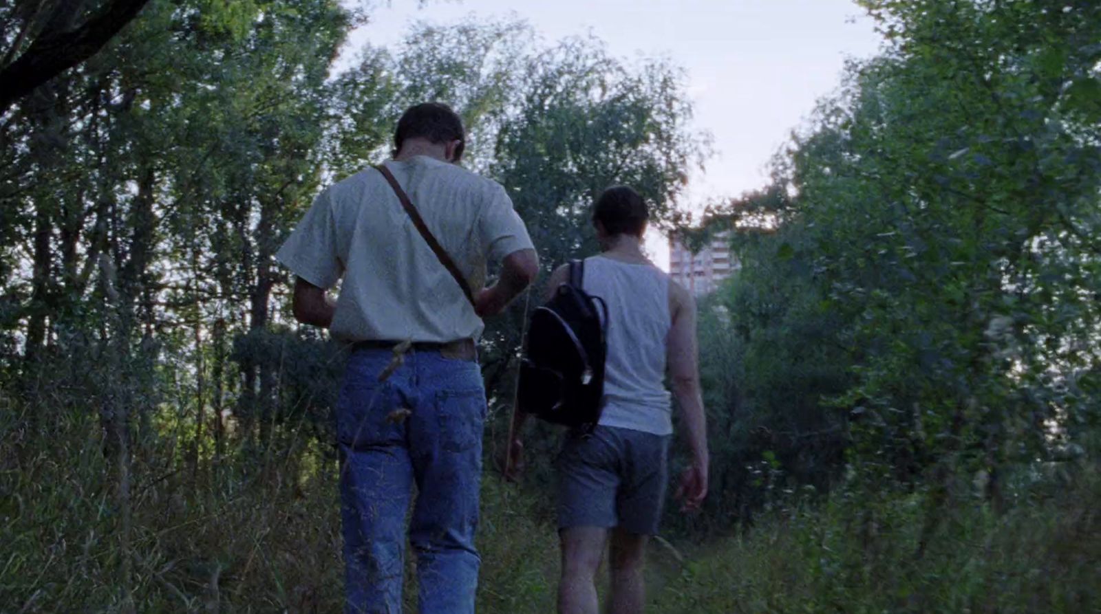 a couple of men walking through a forest