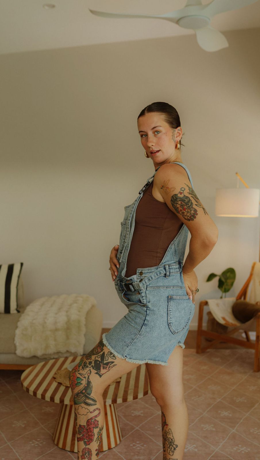 a woman with tattoos standing on a stool
