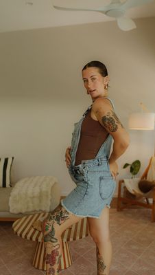 a woman with tattoos standing on a stool